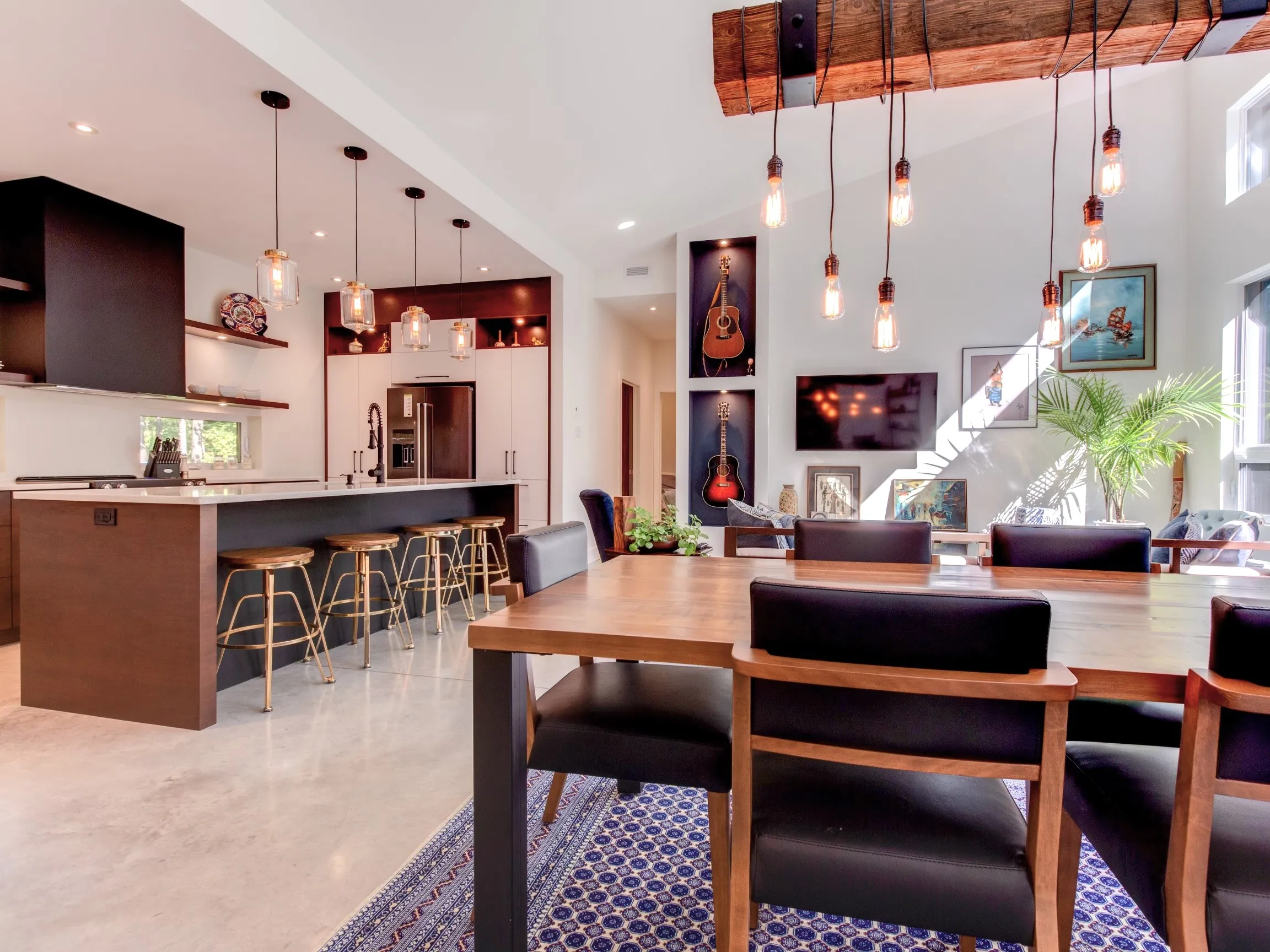 Cuisine moderne ouverte sur un îlot central en bois foncé, avec un plan de travail en marbre et des fauteuils design en cuir.