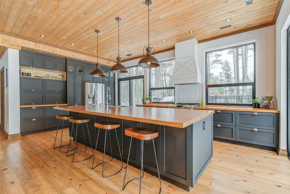 Cuisine design moderne avec îlot central en bois et plans de travail noirs.